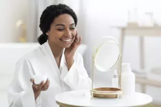 Beauty Rituals. Attractive Black Woman Applying Moisturising Cream On Face