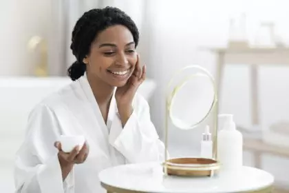 Beauty Rituals. Attractive Black Woman Applying Moisturising Cream On Face