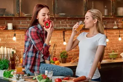 Eat well to be well Young female friends preparing together healthy meal in modern kitchen. Cozy