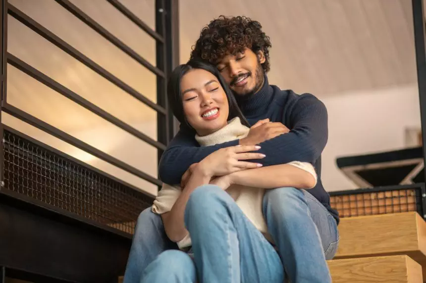 Embraced man with woman sitting on stairs at home