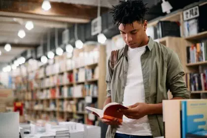 Young black student reading a book in a library,