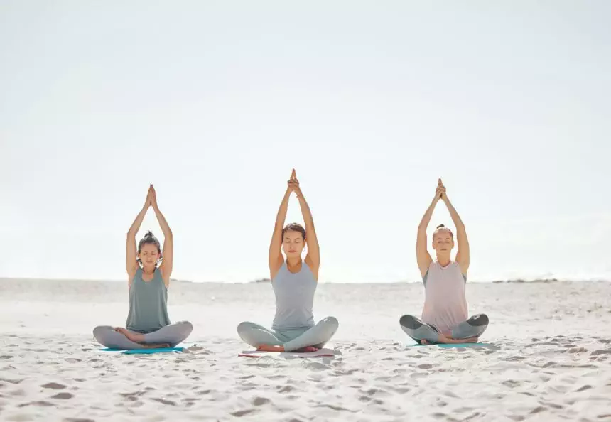 Zen, meditation and yoga at the beach with women for wellness, fitness and health. Stretching, lotu